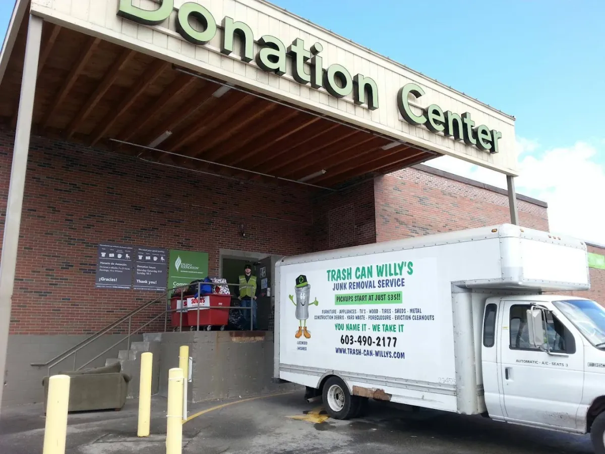 A Trash Can Willy's box truck backed up to a donation center while a crew member unloads