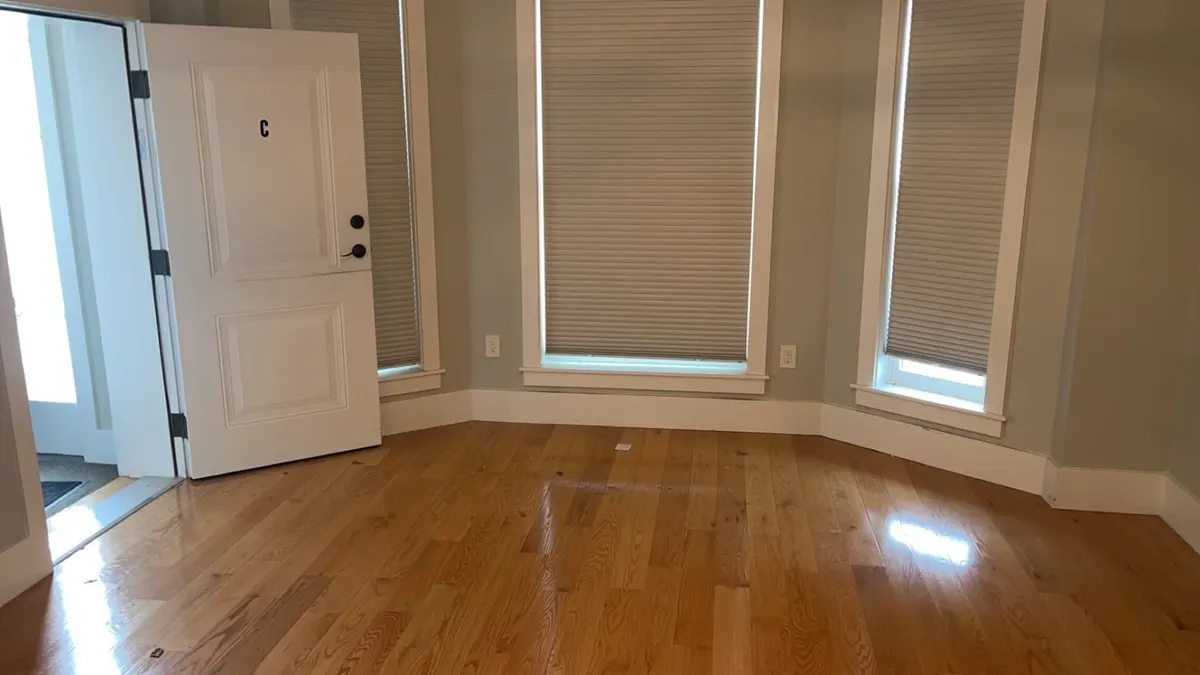 A front room emptied down to bare floor after a Trash Can Willy's crew cleared it