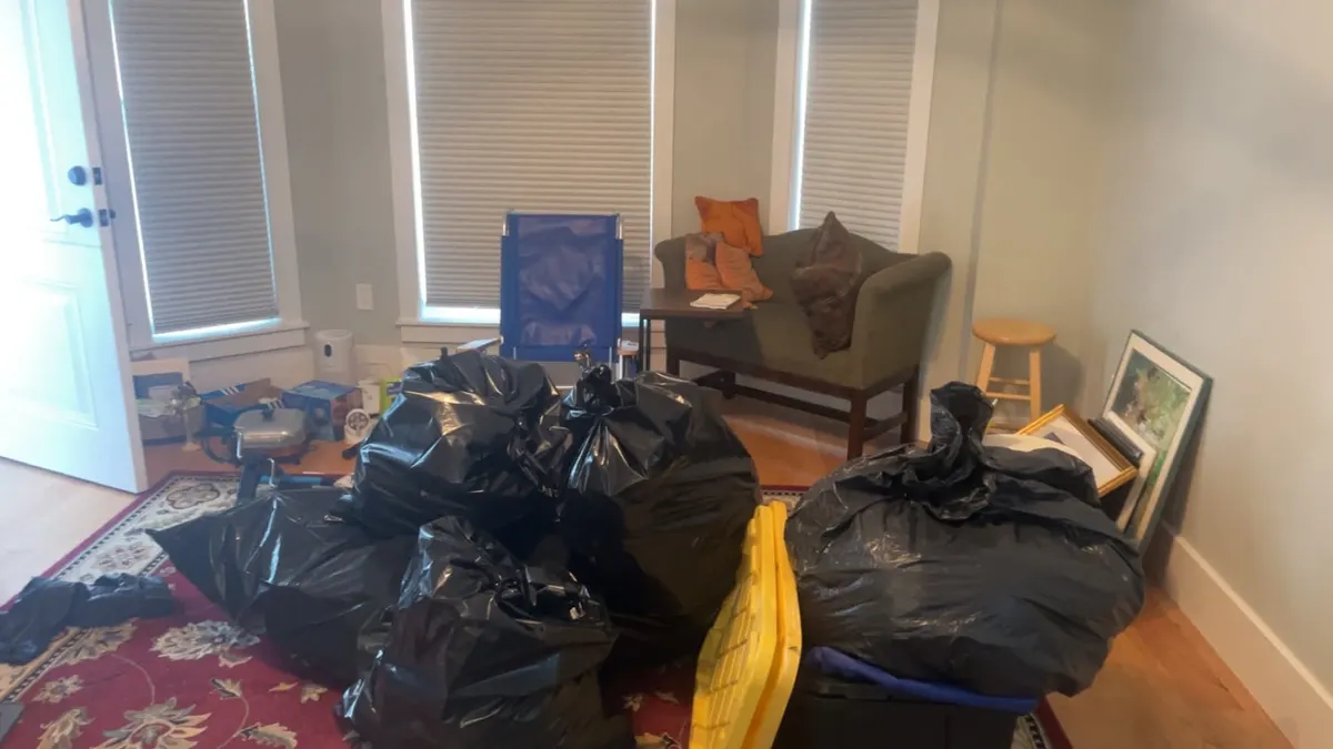 A living room packed with bagged contents and a loveseat, before the crew clears it